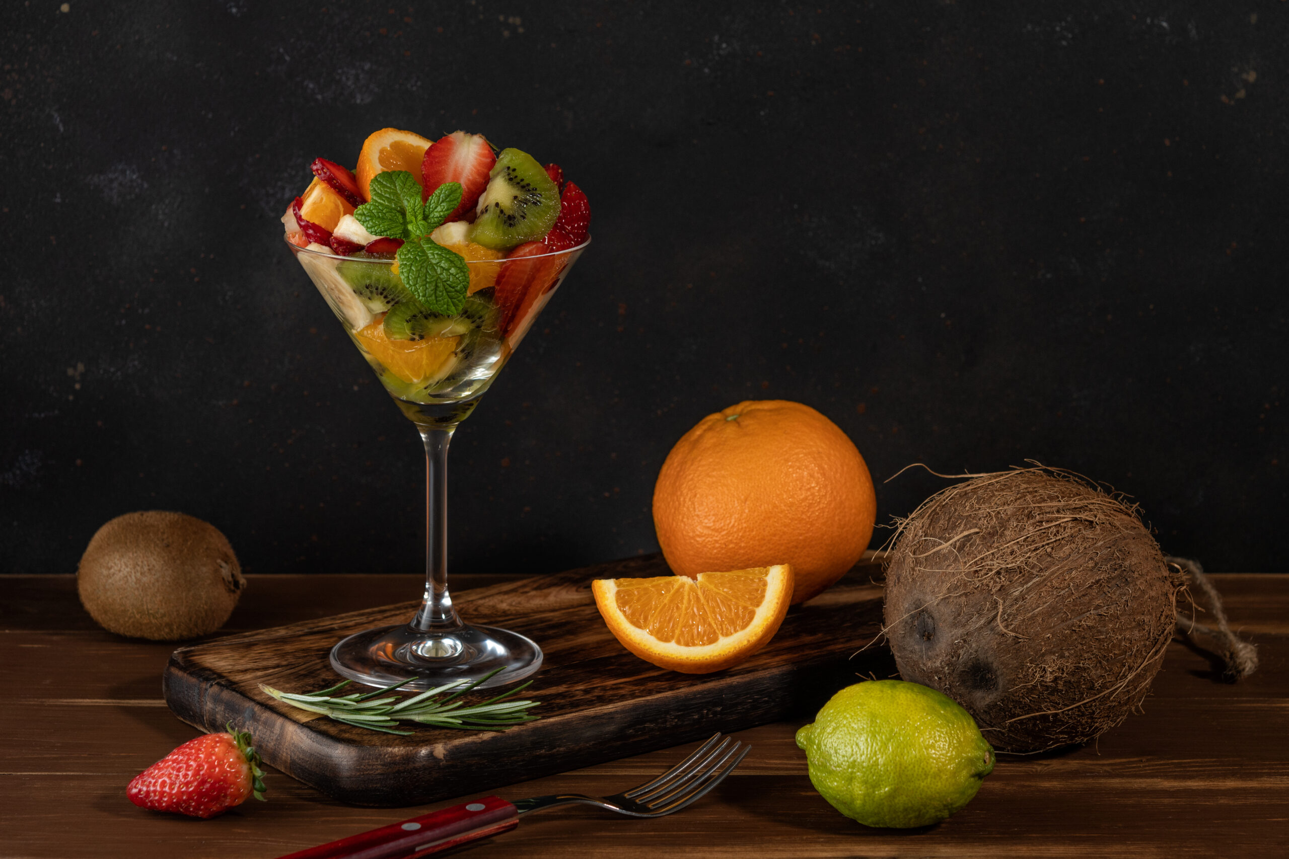 Fruit cocktail in martini glass on wooden table. Food vegan concept